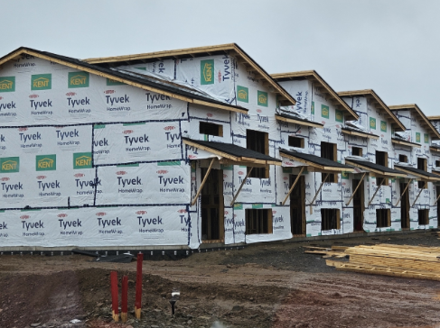 Multi-storey apartment building under construction with wood framing and Tyvek weather wrap installed.