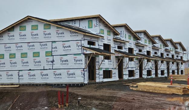 Multi-storey apartment building under construction with wood framing and Tyvek weather wrap installed.