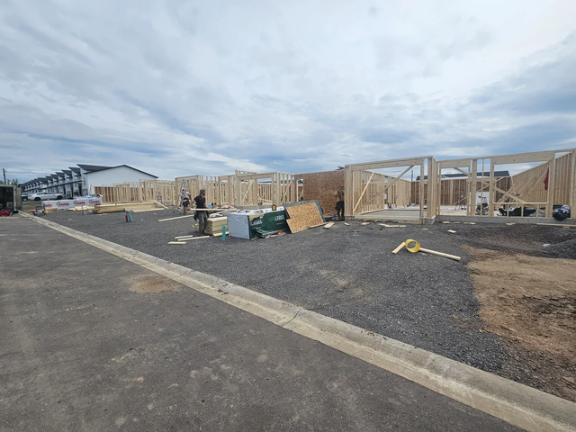Multiple wood-framed residential structures at framing stage with walls framed preparing for trusses..