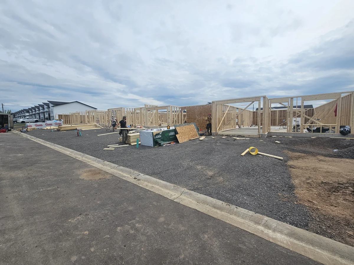 Multiple wood-framed residential structures at framing stage with walls framed preparing for trusses..