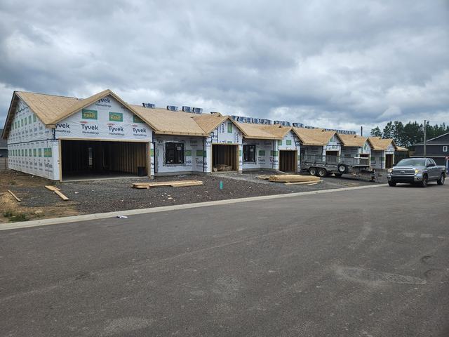 Multiple residential units under construction with framing complete, wrapped in Tyvek house wrap and sheathing installed.