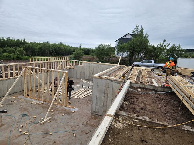 Wood framing walls and floor joists under construction on a concrete foundation basement.
