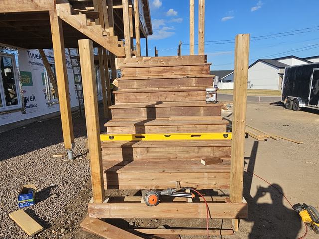 Wooden stair stringers under assembly for residential framing, showing treads and supports in progress.