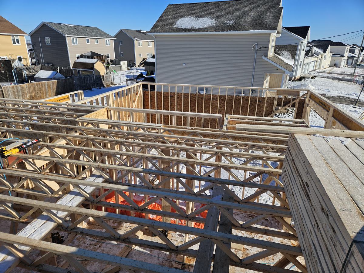 Wood-framed home construction showing joists and beams during the structural framing stage of a residential build.