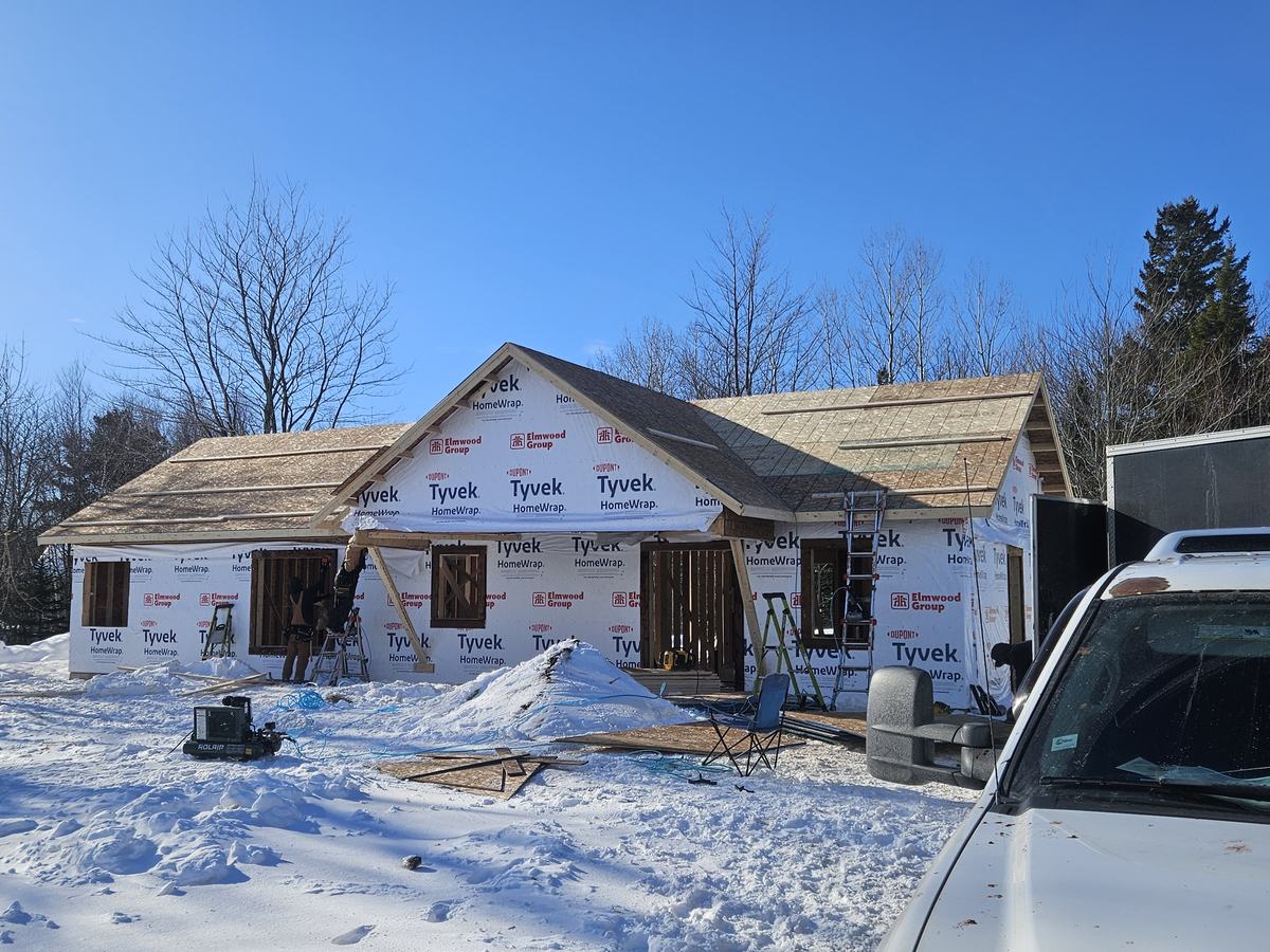 New residential home envelope wrapped in Tyvek HomeWrap during construction phase with roof sheathing complete.
