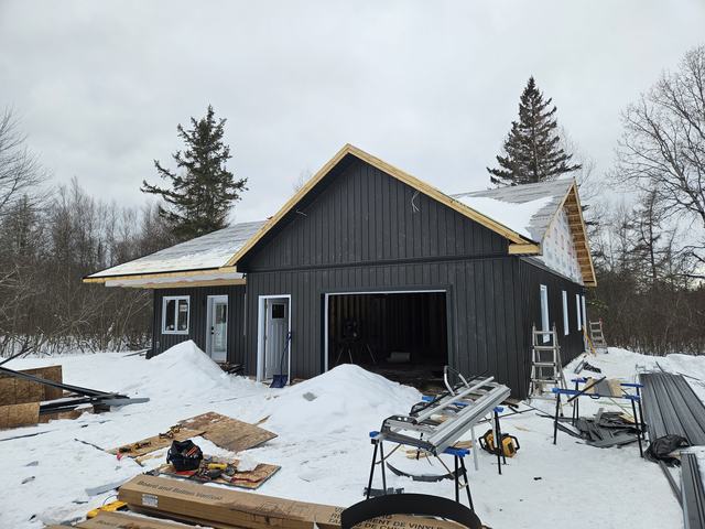 Residential home under construction showing wood framing completed and exterior siding in progress.