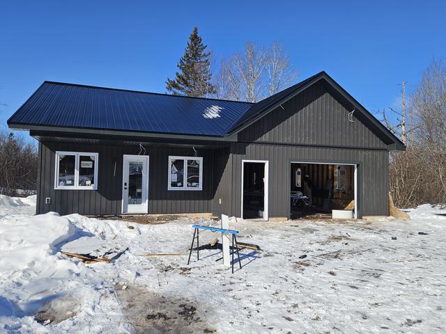 Residential building with completed metal roof and dark exterior siding.